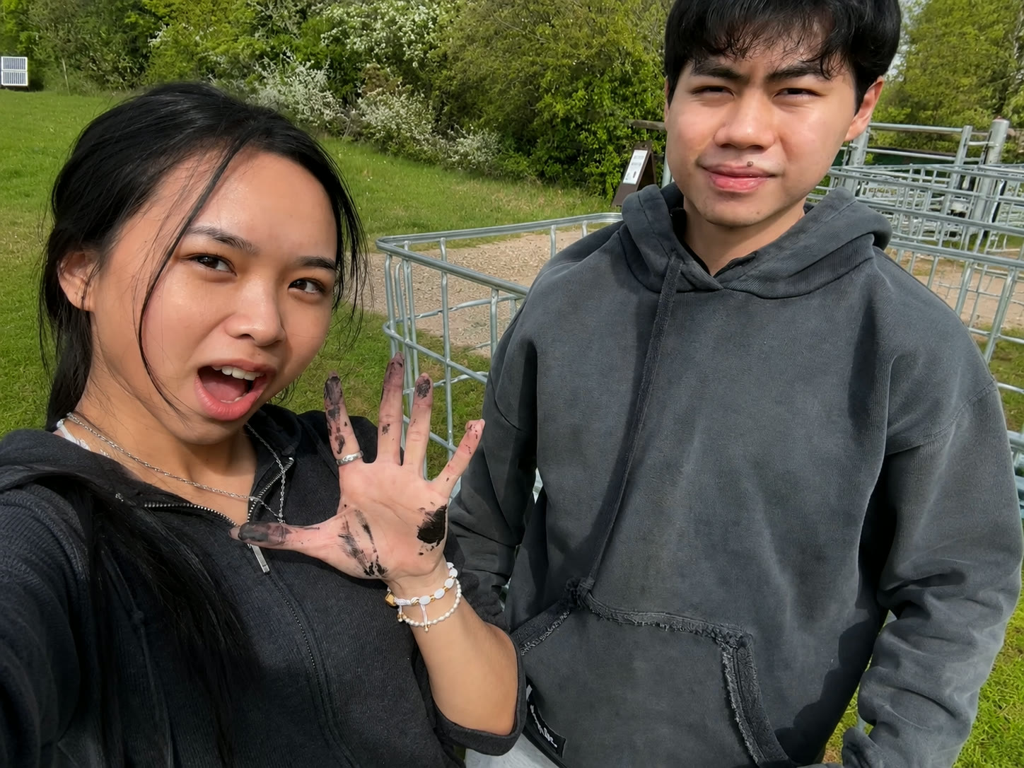 Tam Ann showing her muddy hand with Jaden laughing beside her in the park