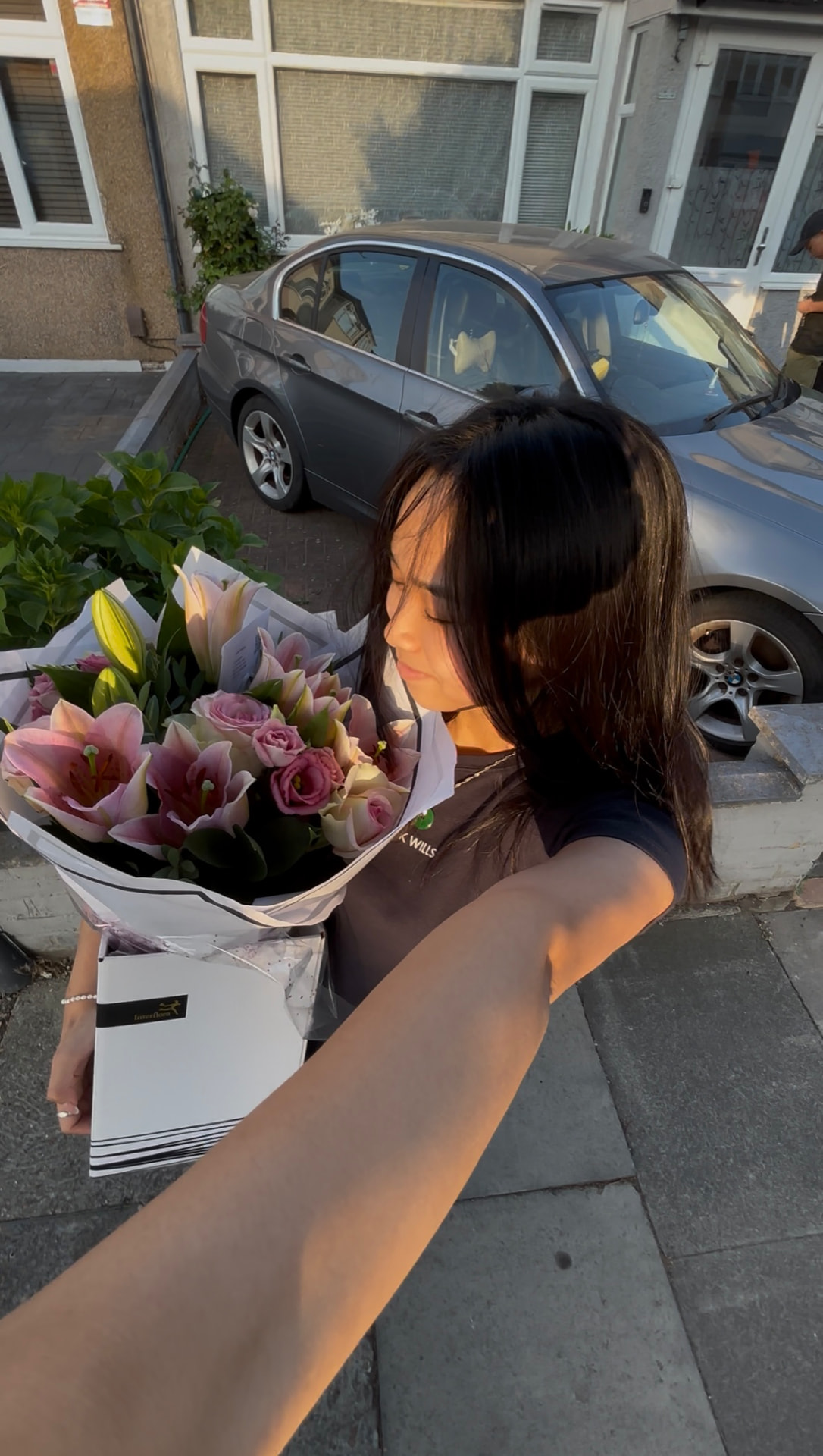 Tam Ann holding a bouquet of pink lilies and roses in golden evening light